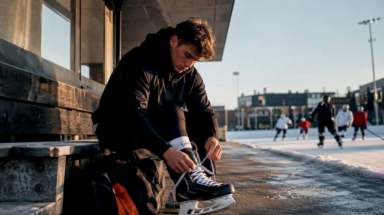 Hockey player tying skates in training hoodie