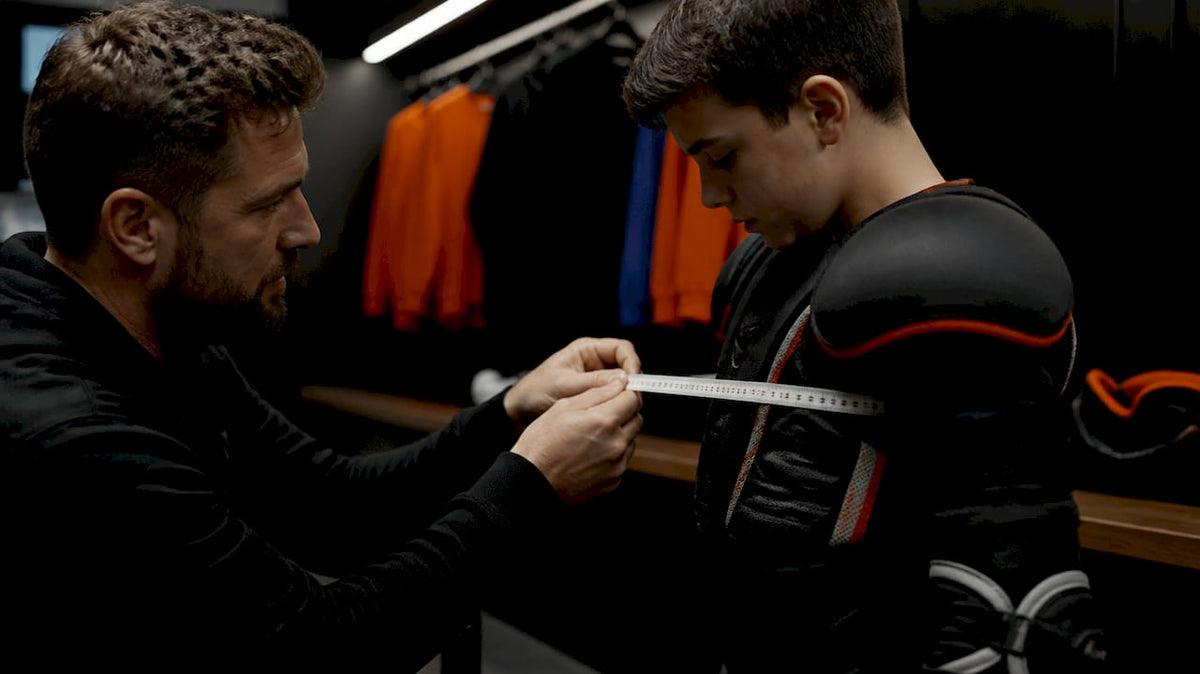Coach measuring player chest with pads