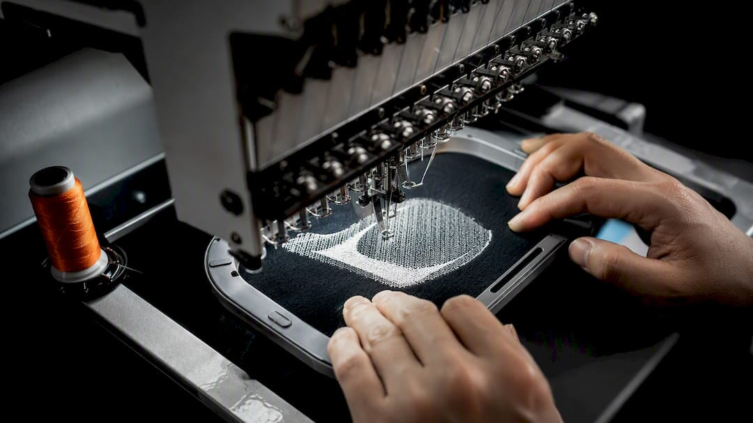Embroidery machine stitching an anonymous logo swatch