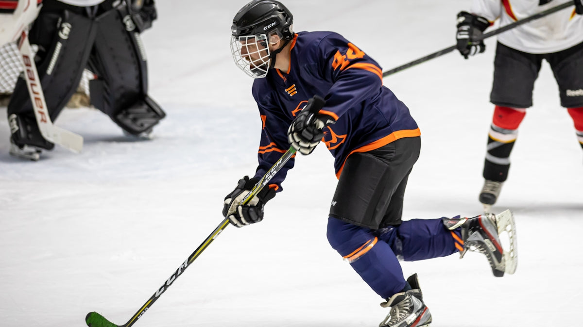 man in blue and white ice hockey jersey holding black and green hockey stick