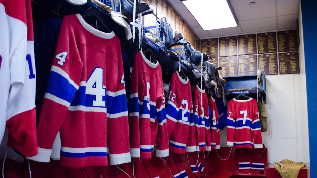 Red and blue hockey jerseys hanging in a locker room.