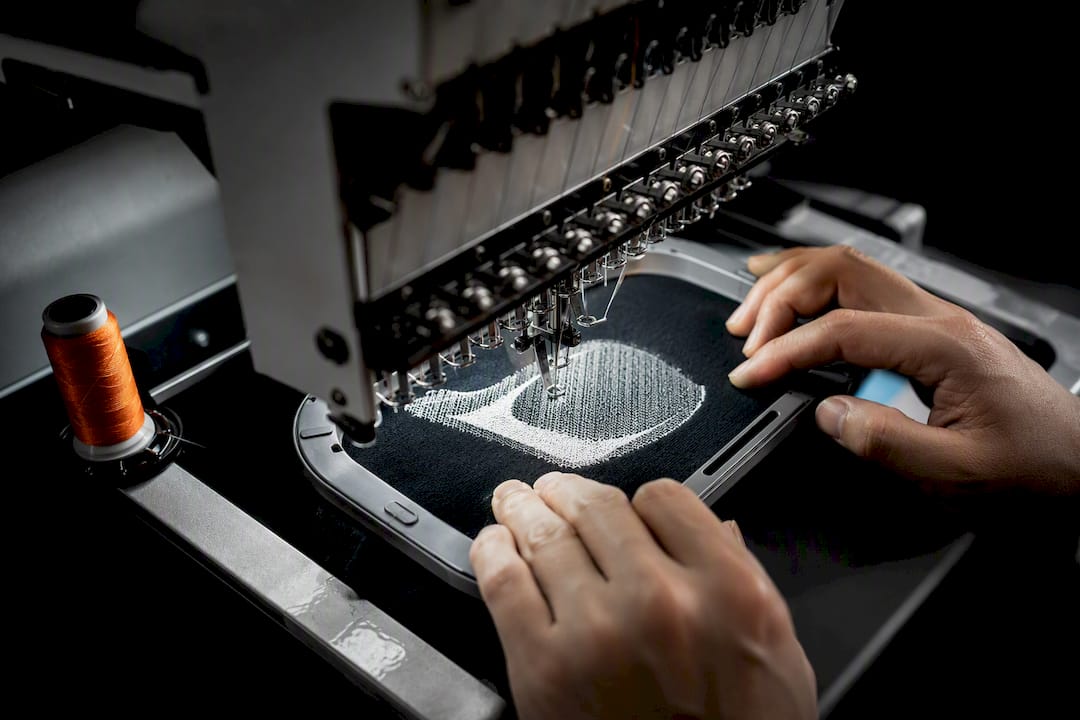 Embroidery machine stitching an anonymous logo swatch