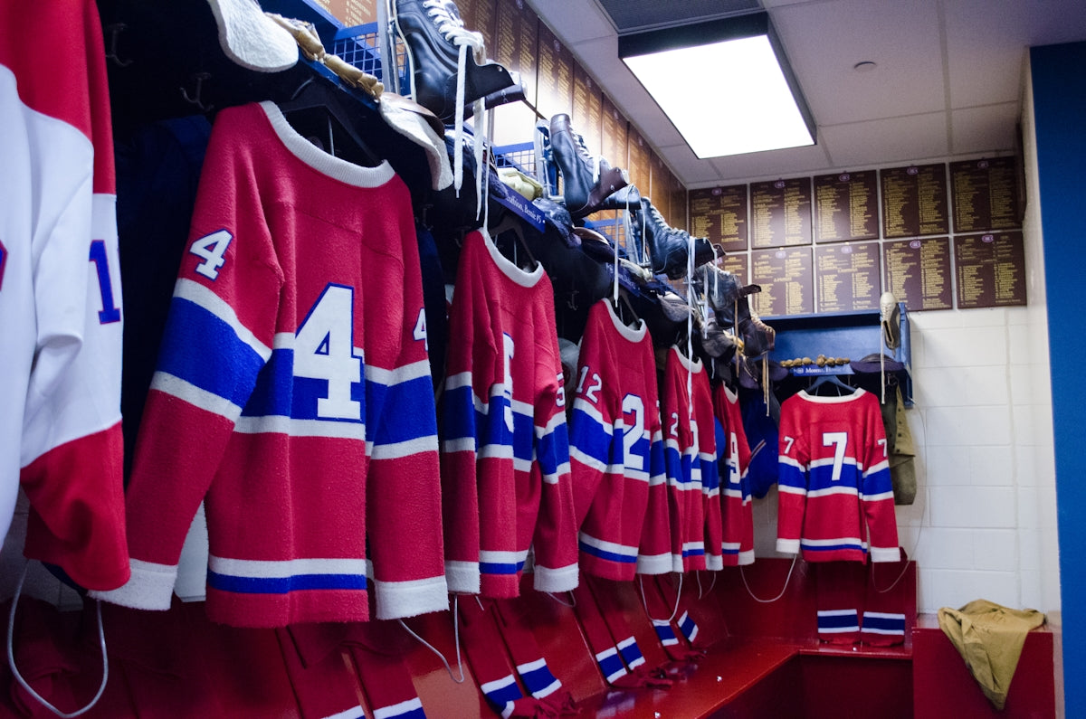 Red and blue hockey jerseys hanging in a locker room.